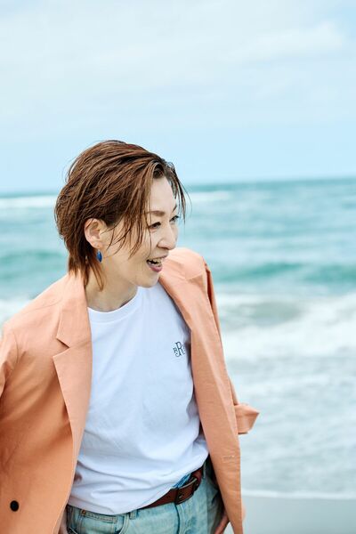 海を背にして笑顔をみせる越乃リュウさん