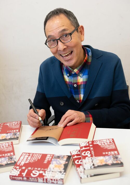 新刊『漫才の一滴　笑吉が教えてくれた「念、縁、運」』にサインを書く里見まさとさん