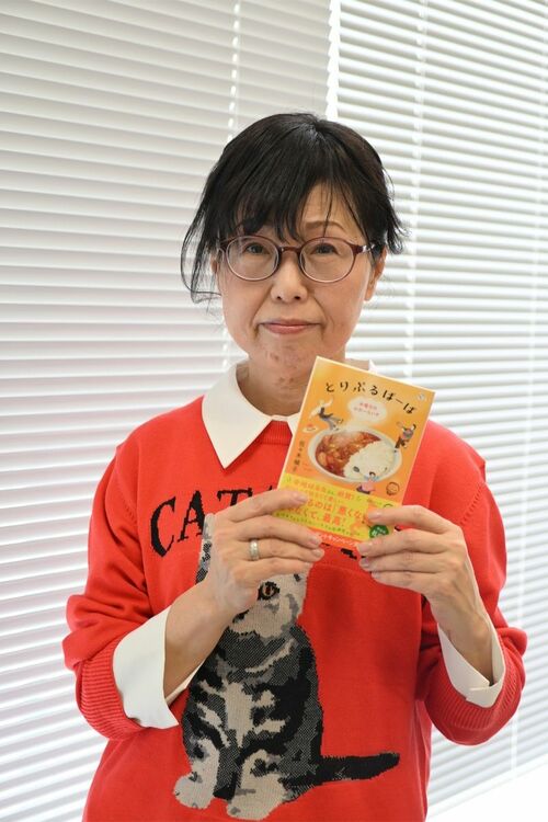 『とりぷるばーば　水曜日のカレーライス』を手にとる佐々木禎子さん